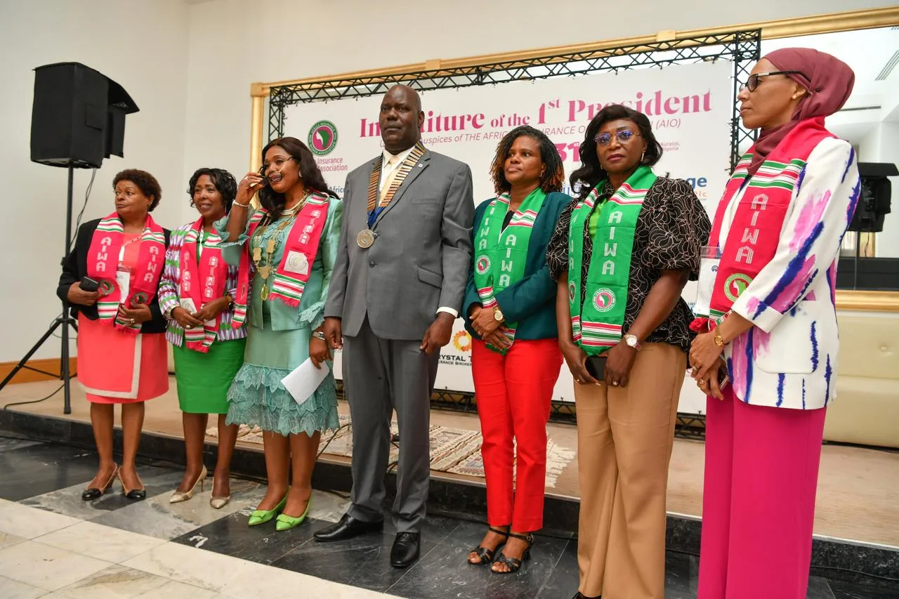 Delegates in AIWA sashes on stage with a dignitary in ceremonial regalia